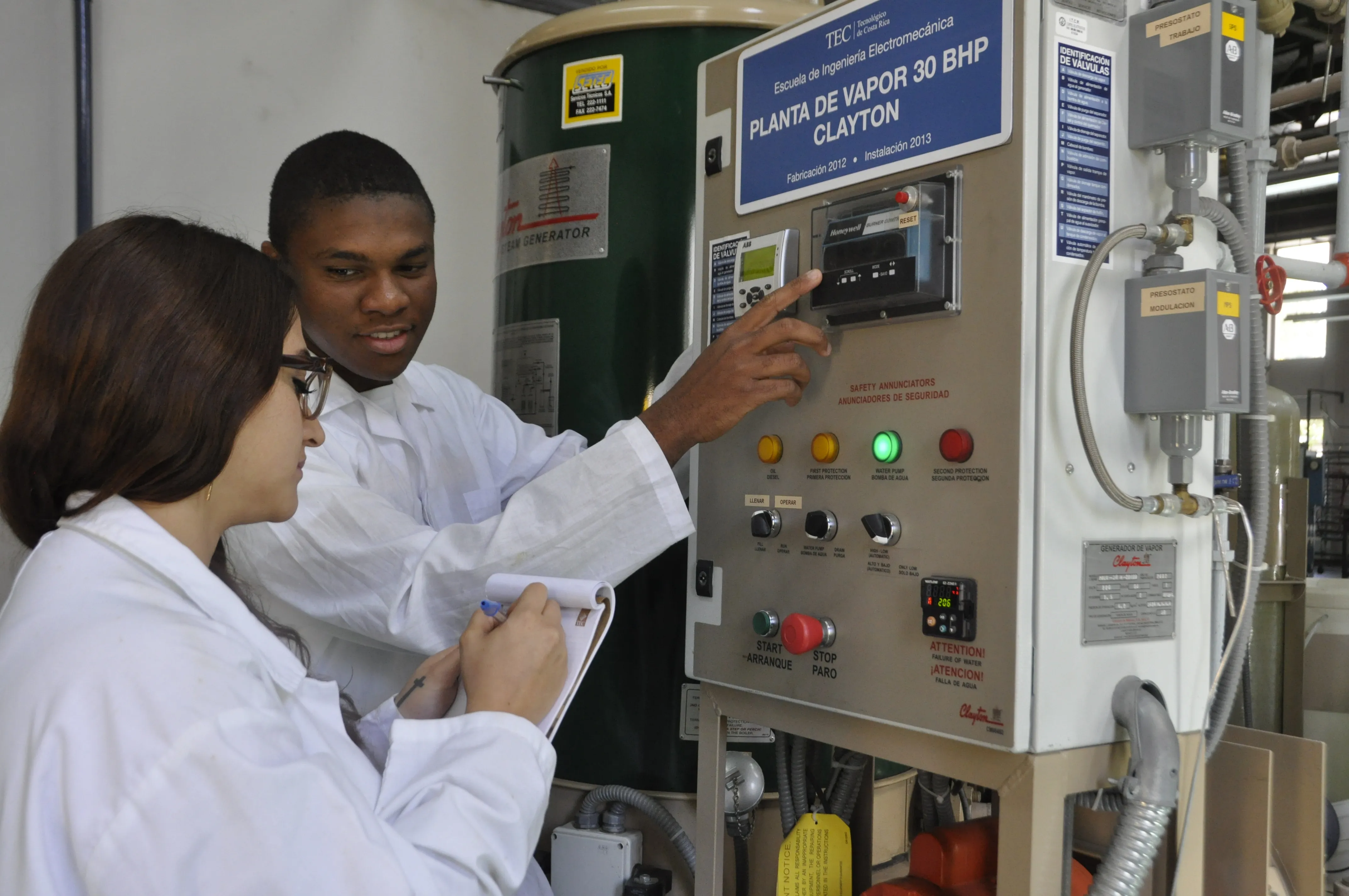 Dos estudiantes utilizando un panel electromecánico