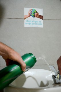 Botella llenándose de agua en un lavatorio.