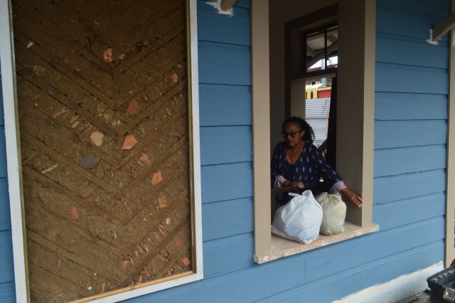 Bernadette Esquivel Morales se asoma por una ventana de la estación del ferrocarril en Heredia durante su restauración. Al lado se aprecia una pared descubierta que deja ver la técnica constructiva original con tierra.