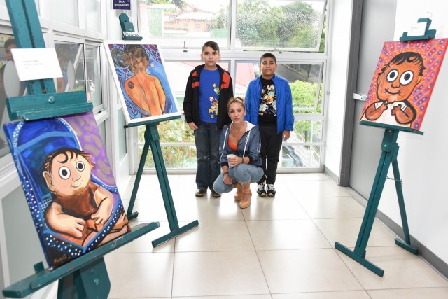 Débora Portilla, Fausto y Fidel, esposa e hijos de Francisco Munguía, posan junto a las caricaturas que Munguía hizo de ellos en la biblioteca del Campus TEC San José.