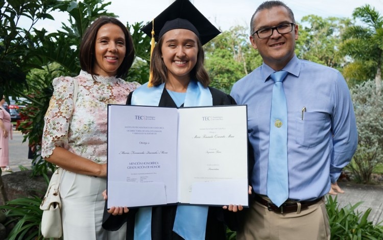 la joven muestra el título junto a sus padres