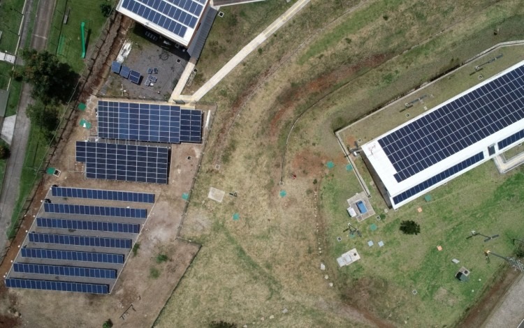 Vista aérea de los paneles solares, tanto en piso como en el tejado de un edificio.