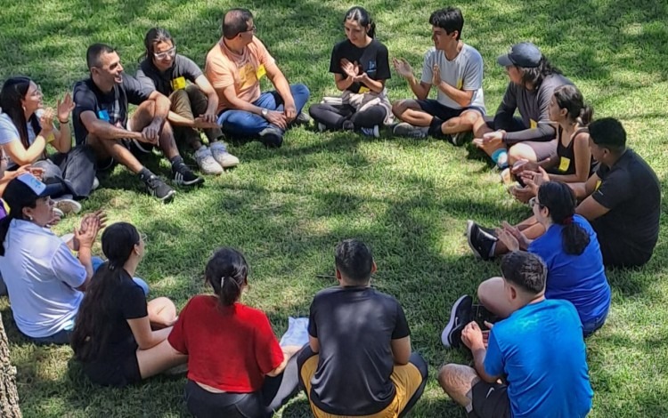 Imagen de varias personas sentadas recibiendo una charla de integración.