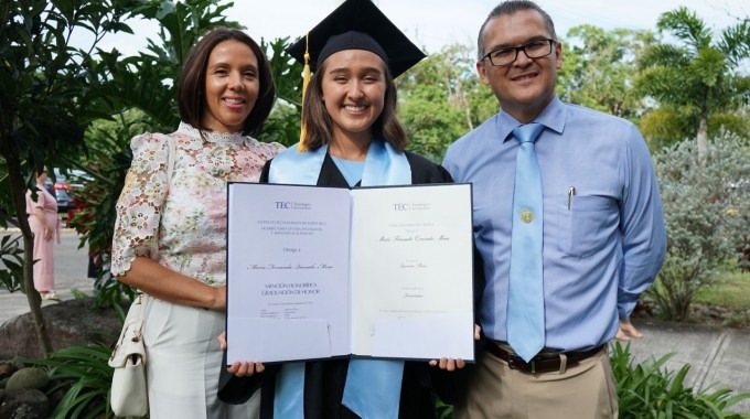 la joven muestra el título junto a sus padres