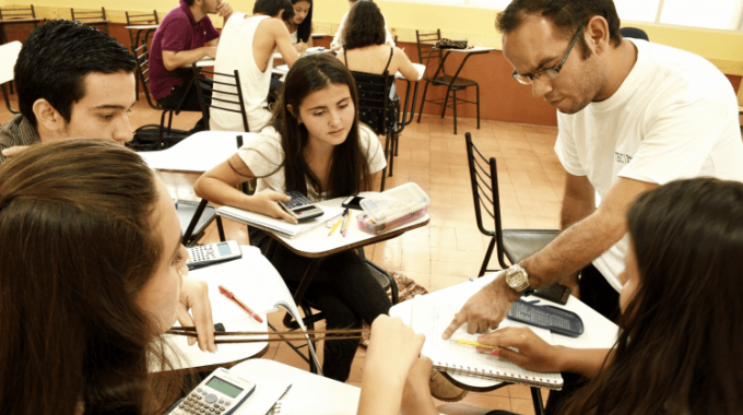 grupo de estudiantes sentados en aula con docente de matemática 