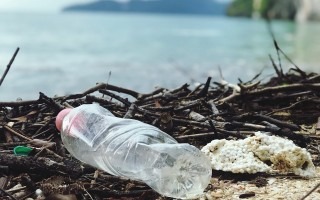 botella plástica y basura frente a playa