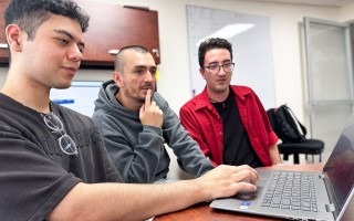 los jóvenes analizan código en la computadora, junto al docente