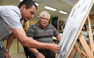 Un adulto mayor aprende a dibujar con la ayuda del profesor.
