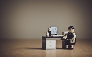 Figura de LEGO de un empresario desesperado frente a su escritorio