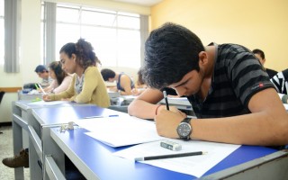 Imagen de varios estudiantes (hombres y mujeres) realizando un examen en un aula.