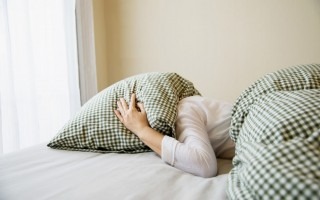 imagen de una mujer con su cabeza bajo la almohada.