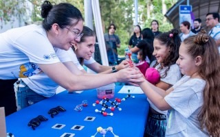 Imagen de unas niñas con unas estudiantes en los stands de los eventos.