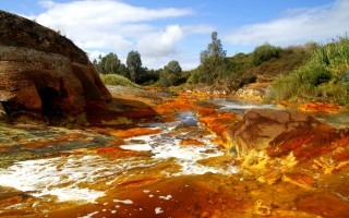La imagen es una fotografía del río tinto. El objetivo principal de la fotografía es mostrar el color rojizo del agua. 