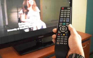 mano con control remoto y televisión