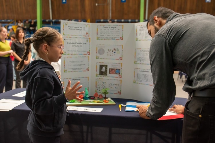 Imagen de una niña con un profesor en la feria científica