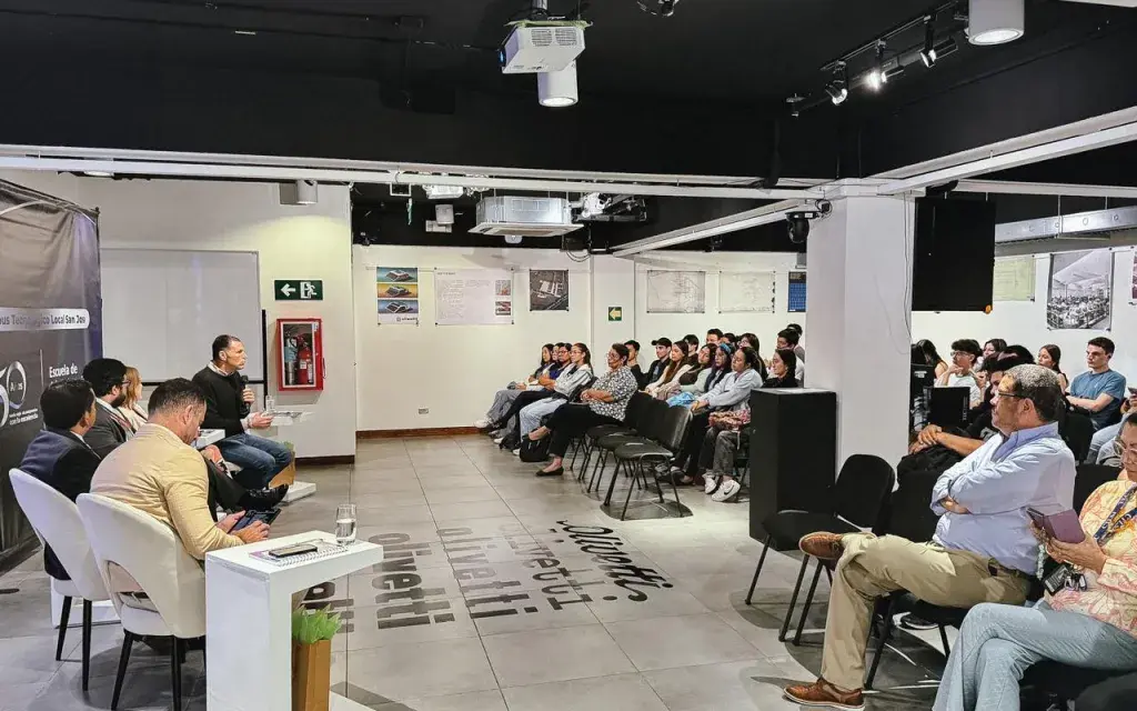 La fotografía muestra un plano general de las personas asistentes y en la mesa principal del evento.