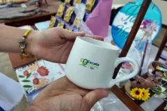 Manos sostienen taza alusiva al aniversario de la Escuela